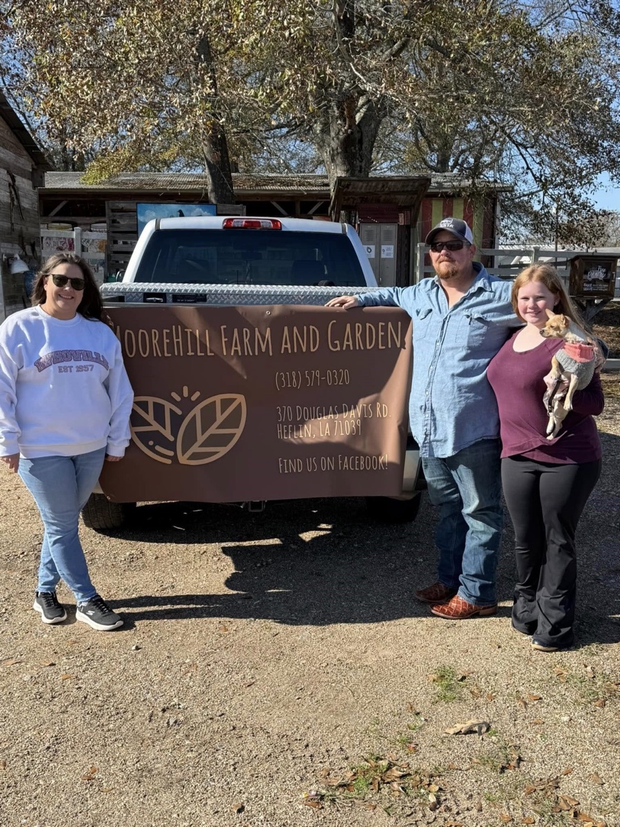 The Moore Hill Farm and Garden family standing with their farm sign
